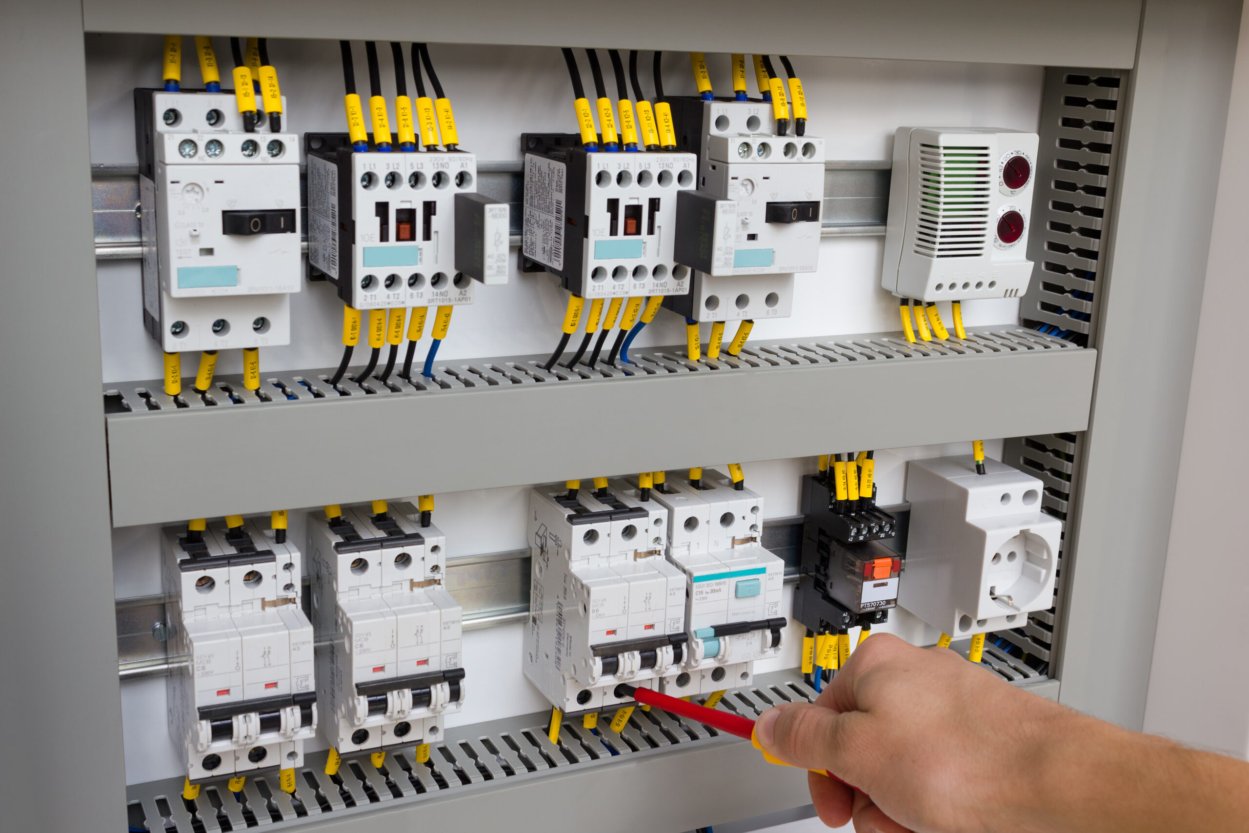 Technician working at electrical cabinet (using a screwdriver).